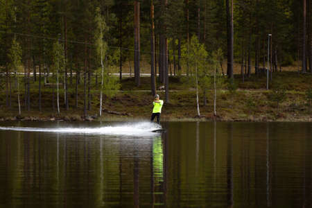 Fagersta, Sweden - Maj 26, 2020: Young wakeboarder rides a wakeboard on the lake. Wakeboarding is...