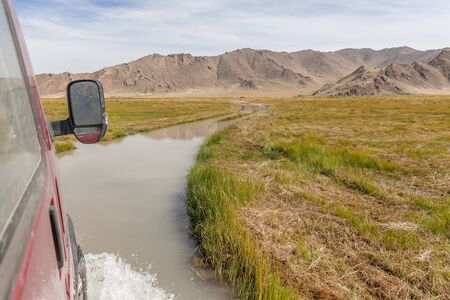 4WD car wades river. Journey of river on SUV car. Mongolia - Altai. photo made from inside carの写真素材