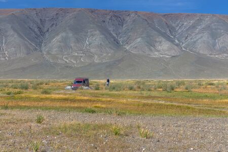 Car and motorbike on road in the desert mountain of the Mongoliaの写真素材
