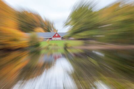 Abstract photo, The house is surrounded by an autumn forest, standing on the shore of a lake. photographed with different effects of motion and zoom. Colorful textured background. long shutter speed.の写真素材