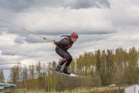Fagersta, Sweden - Maj 07, 2020: Teen girl make an extreme jump on wakeboarding, around there are a lot of splashes, Upside down on a wakeboard.のeditorial素材