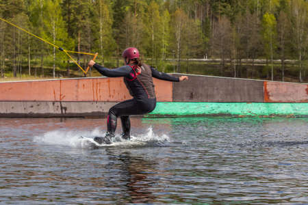 Fagersta, Sweden - Maj 26, 2020: Young wakeboarder rides a wakeboard on the lake. Wakeboarding is cool, extreme sportのeditorial素材