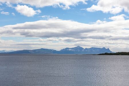 A mystical fjord in Norway with mountains and fog hanging over the water in polar day. midnight sun, selective focusの写真素材