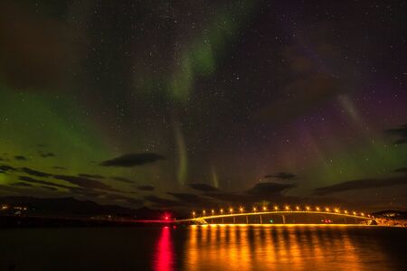 northern lights, Polar lights with many clouds and stars on the sky over bridge to Sommaroy, Lofoten islands, Norway, long shutter speed.の写真素材