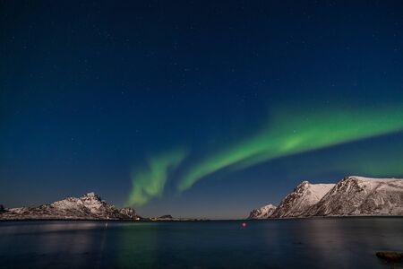 Aurora borealis, northern lights over fjord mountains with many stars on the sky in Lofoten islands, Norway, long exposure.の写真素材