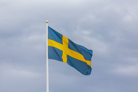 Swedish flag as proudly fluttering in the wind against a blue sky.の写真素材