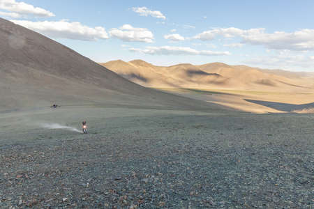 A motorcyclist tries his motorcycle on the hills of Mongoliaの写真素材