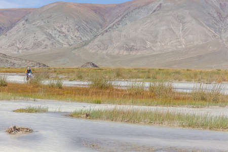 A motorcyclist is crossing white, mountain river on a motorcycle. Mountain Altai, Mongoliaの写真素材