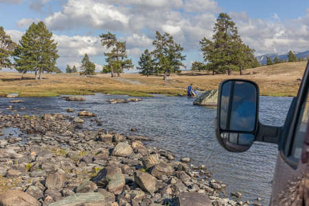 Altai, Mongolia - June 14, 2017: A motorcyclist pushes a motorcycle along a road flooded with water. Altai, Mongoliaのeditorial素材