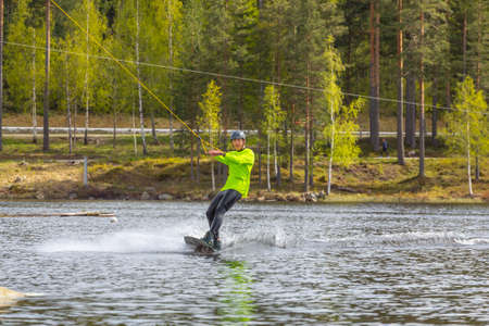 Fagersta, Sweden - Maj 26, 2020: Young wakeboarder rides a wakeboard on the lake. Wakeboarding is cool, extreme sportのeditorial素材