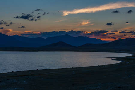 Beautiful blue ridge mountain sunset with orange sky. Mountain Lake in Mongolian Altai.の写真素材