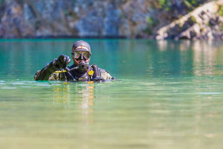 diver looking at the camera. Head on the surface. Gestures that he goes under water. thumbs downの写真素材