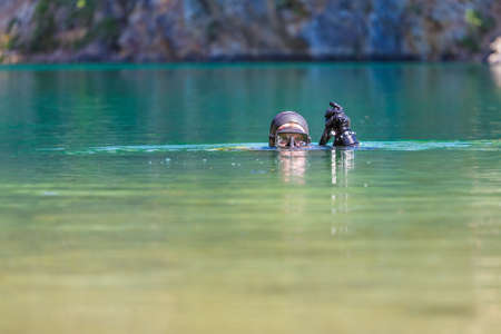the diver plunges into the water, looks into the camera. Head on the surfaceの写真素材