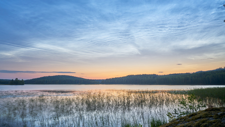 Nightless night in finnish countryside with lake, sunrise and night cloudsの写真素材