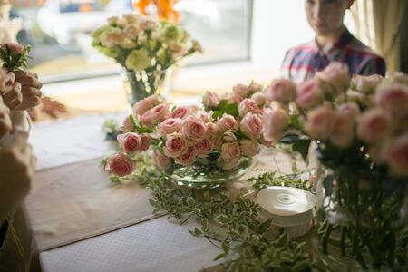pink garden roses on a bowl on the table indoors with blured human on a background in natural lightの写真素材