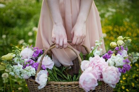 girl holding a basket with flowers: peonies and lisianthusの写真素材