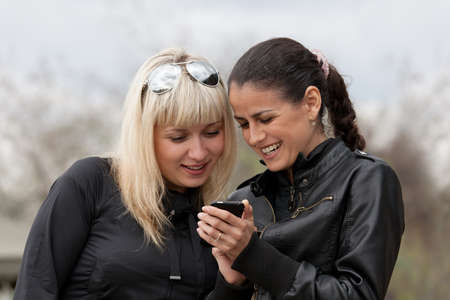 Two young girls considering something in the smartphone.の写真素材