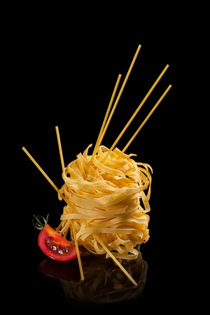 Noodles and spaghetti with a piece of tomato on a black backgroundの写真素材