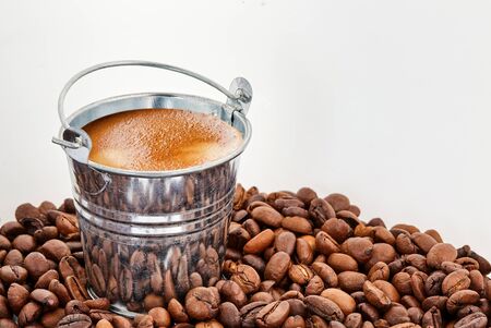 A bucket of coffee in coffee beans on a white isolated backgroundの写真素材