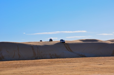 Several off-road vehicles in safari, the first car in a steep descent from the hillの写真素材