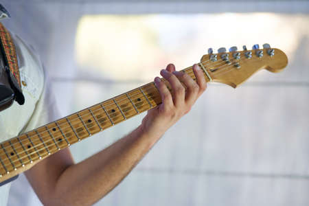 close-up detail of the musician's hands playing his electric guitarの写真素材