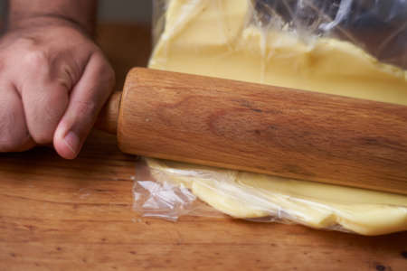Man with rolling pin stretches butter for preparation with fat inside a transparent bag. smelly kitchenの写真素材