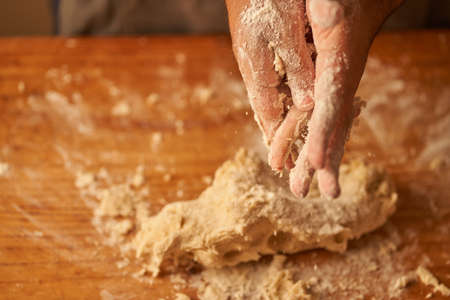 hands of a cook with leftover dough