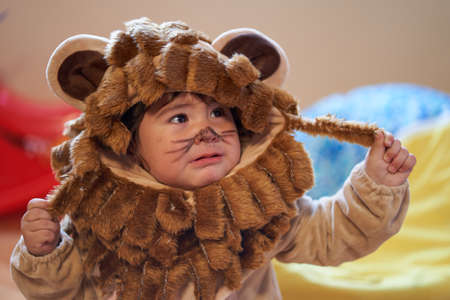 boy in lion costume looks worried as he holds up his mane. worriedの写真素材