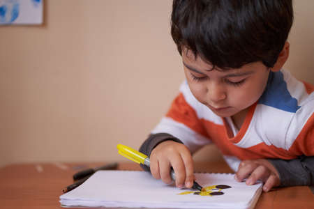 child looks at his drawing while coloring itの写真素材