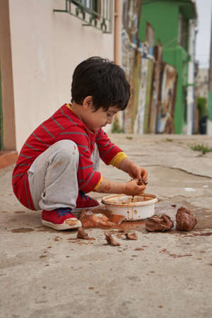 Boy kneeling with red shirt makes figures with clay. molding clay.の写真素材