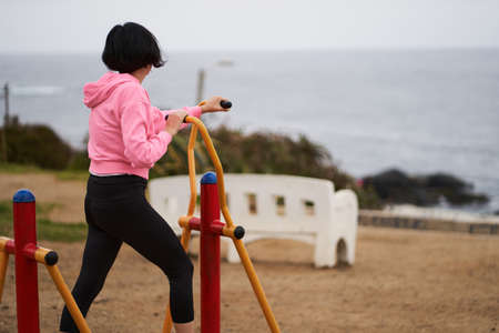 Woman in public square performs arm and leg exercises. Sports session.の写真素材