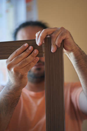 Man assembles wooden furniture. Assembling furniture at home. Carpentry sessionの写真素材
