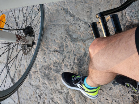 Close up of male legs and bicycle wheel on stone pavement background.の写真素材