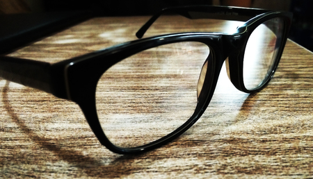 Black colour spectacles on wooden tableの写真素材