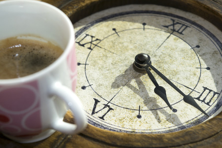 concept of rise and coffee with a coffee cup and an old watchの写真素材