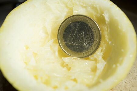 concept of crisis and squeezed economies through the image of squeezed lemon and some coins