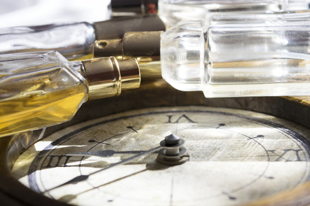 concept of time passing charm and beauty that wither through the image of a clock and some perfume bottlesの写真素材