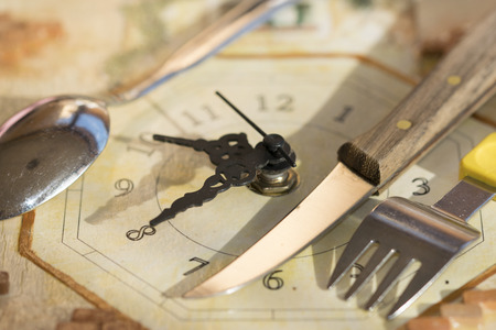 lunch time concept with a clock and cutleriesの写真素材