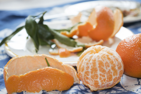 Two ripe clementines one peeled and one wholeの写真素材