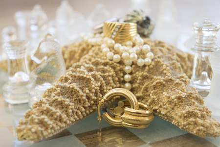 family jewels on a starfish between the pieces of a glass chessboardの写真素材