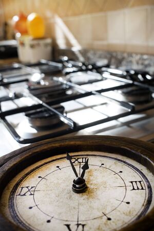 concept of lunch time with an old skeleton clock on a stove-top