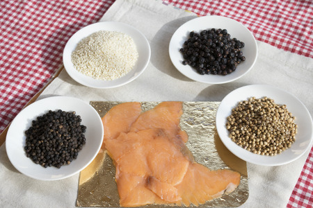top view of smoked salmon in slices with spices various on saucersの写真素材