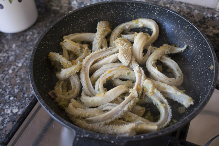 cooking tripe in pan with onion and chopped vegetablesの写真素材