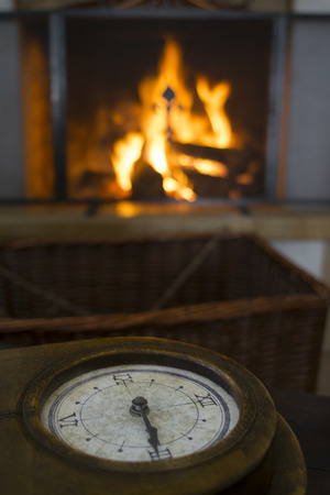 concept of time with an ancient clock in front at a fireplaceの写真素材