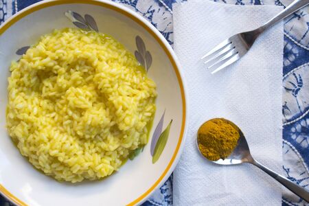 flat lay of a dish of saffron rice with a spoon of the principal ingredientの写真素材