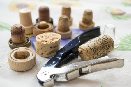 corkscrew with inserted wine cork and series of stoppers on the background