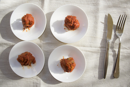 meatballs in tomato sauce presented in four white saucerの写真素材