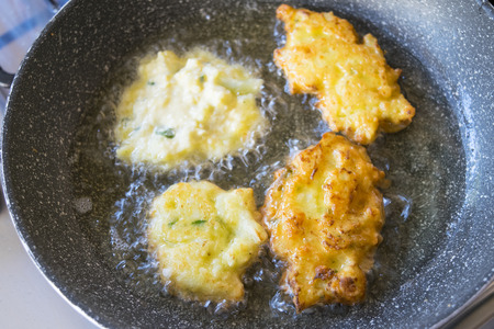 vegetarian fritters frying in pan with boiling oilの写真素材