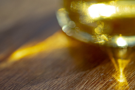 pattern solar through a glass bottle oil reflected on a wooden baseの写真素材