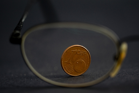 concept of family saving money with a cent photographed through a pair of specsの写真素材